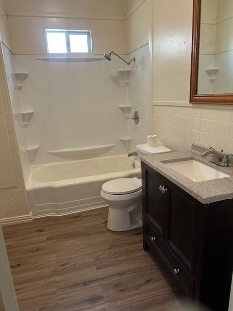 full bathroom with tasteful backsplash, wood finished floors, vanity, bathtub / shower combination, and toilet