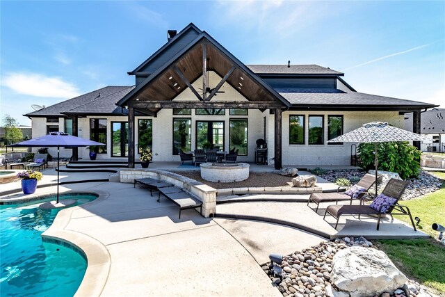 back of house with a patio, roof with shingles, an outdoor pool, and brick siding