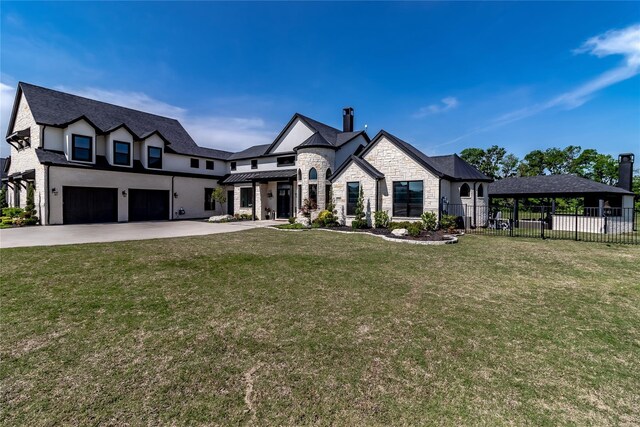view of front of home with fence, an attached garage, stone siding, a standing seam roof, and driveway