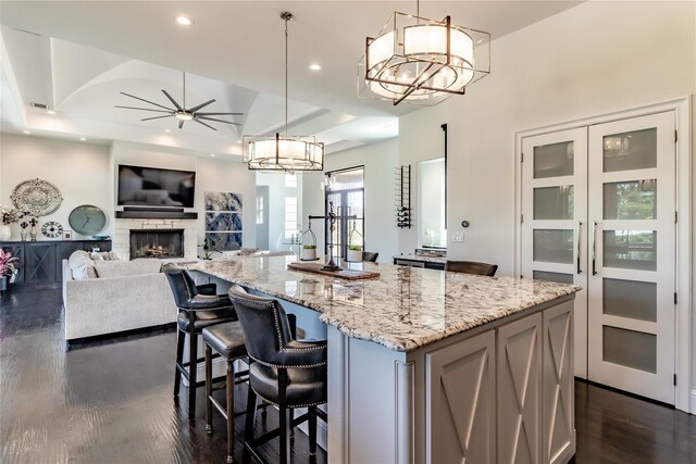 kitchen with dark wood-style flooring, light stone counters, appliances with stainless steel finishes, a sink, and a center island