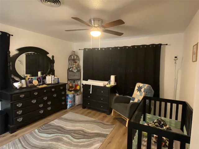 bedroom featuring wood finished floors, visible vents, and a ceiling fan