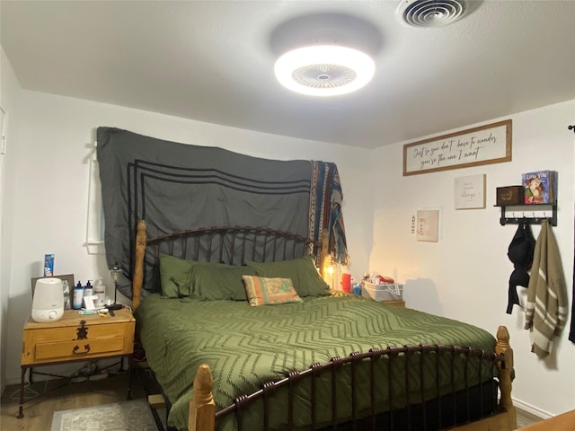 bedroom with wood finished floors, visible vents, and baseboards