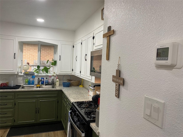 kitchen featuring white cabinetry, stainless steel microwave, light countertops, green cabinets, and black range with gas stovetop