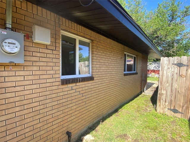 view of property exterior featuring fence and brick siding