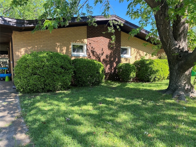 view of home's exterior featuring brick siding and a lawn