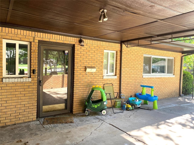 view of exterior entry featuring a patio area and brick siding