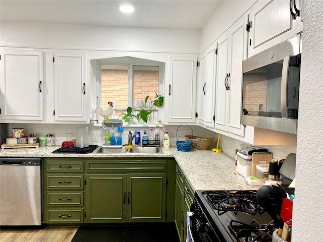 kitchen with white cabinets, stainless steel appliances, a sink, and green cabinets