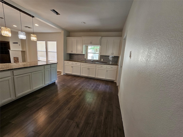 kitchen with backsplash, a textured wall, dark wood-style flooring, pendant lighting, and white cabinetry