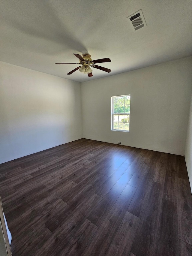 unfurnished room with a ceiling fan, visible vents, and dark wood-style flooring