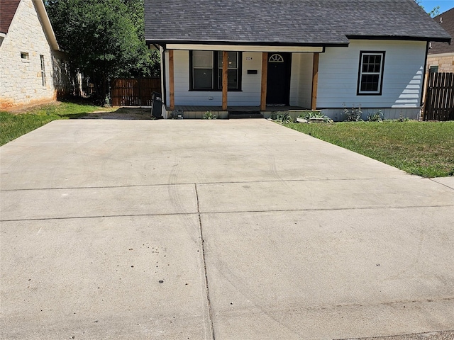 view of front of home with a shingled roof, covered porch, and fence
