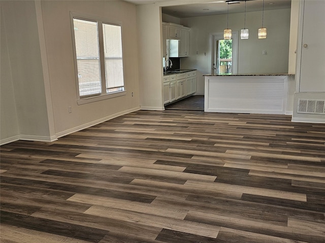interior space featuring visible vents, baseboards, dark wood-style floors, and a sink