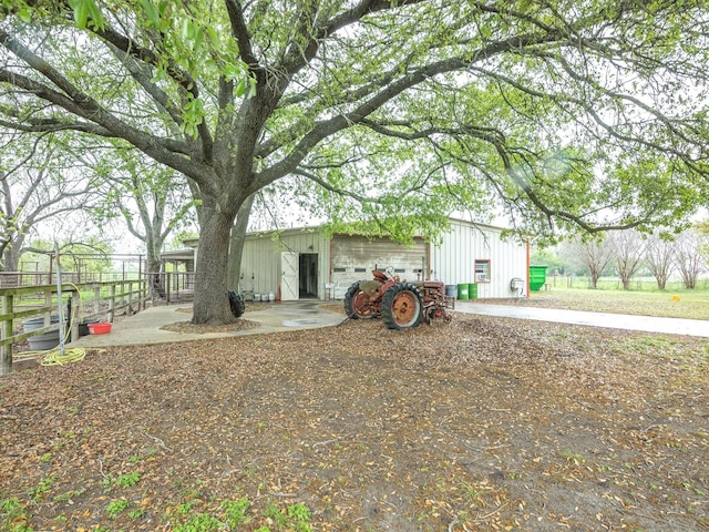 view of yard featuring a garage, fence, an outdoor structure, and a pole building
