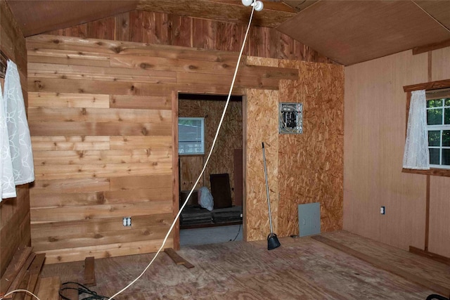 empty room with lofted ceiling and wooden walls