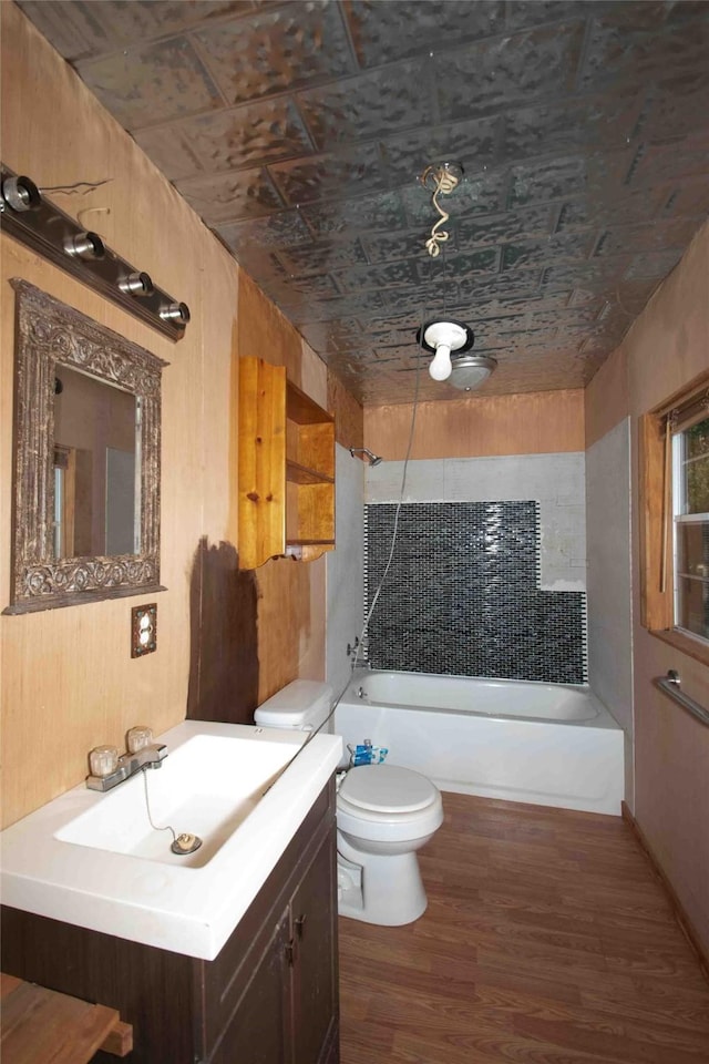 bathroom featuring wood finished floors, shower / bath combination, toilet, vanity, and an ornate ceiling
