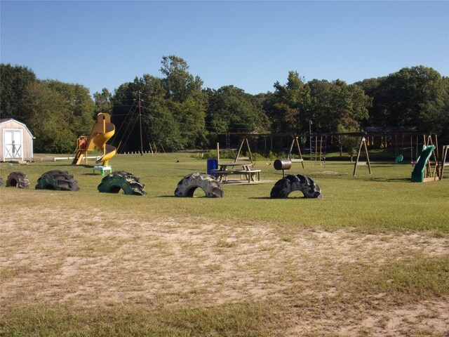 view of property's community with a yard, a playground, and a storage unit