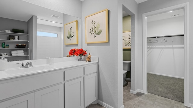 full bath with a walk in closet, visible vents, toilet, and vanity