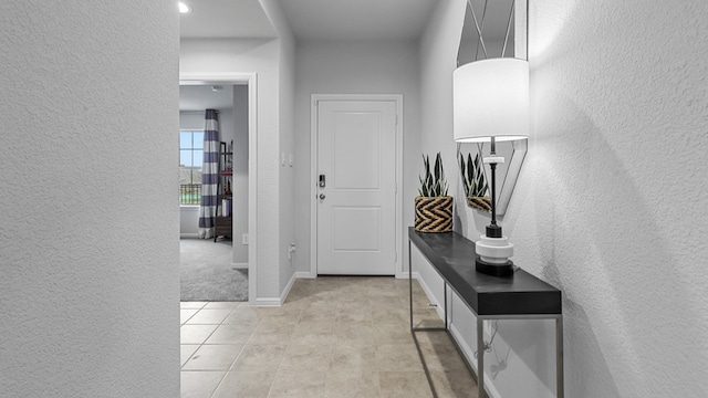 foyer with baseboards, a textured wall, and light tile patterned floors
