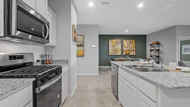 kitchen featuring visible vents, appliances with stainless steel finishes, open floor plan, and a sink
