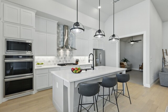 1808 Wren St, Argyle, TX 76226 - kitchen featuring wall chimney exhaust hood, stainless steel appliances, backsplash, light wood-type flooring, and open floor plan