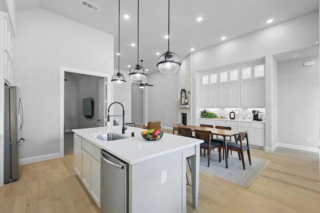 1808 Wren St, Argyle, TX 76226 - kitchen with a sink, stainless steel appliances, a center island with sink, white cabinets, and light wood-style flooring