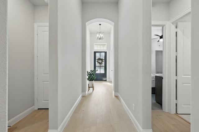 1808 Wren St, Argyle, TX 76226 - hallway featuring light wood-style flooring, arched walkways, and a chandelier
