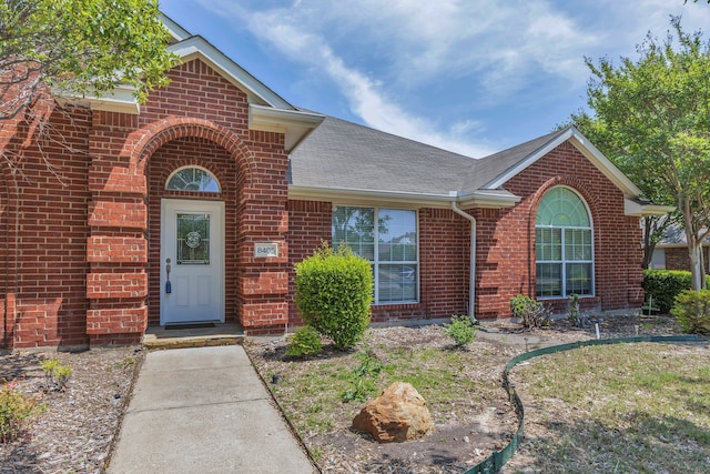 8405 Evening Star Dr, Rowlett, TX 75089 - view of exterior entry with brick siding and roof with shingles