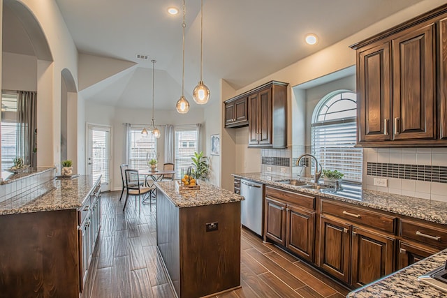 kitchen with a center island, stainless steel dishwasher, a wealth of natural light, and light stone countertops