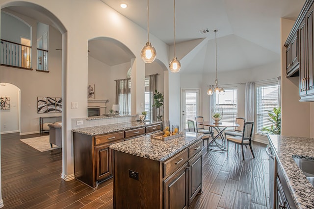 kitchen featuring light stone counters, dishwasher, baseboards, dark wood-type flooring, and visible vents