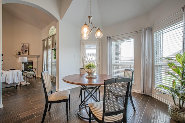 dining room featuring arched walkways, dark wood finished floors, baseboards, and plenty of natural light