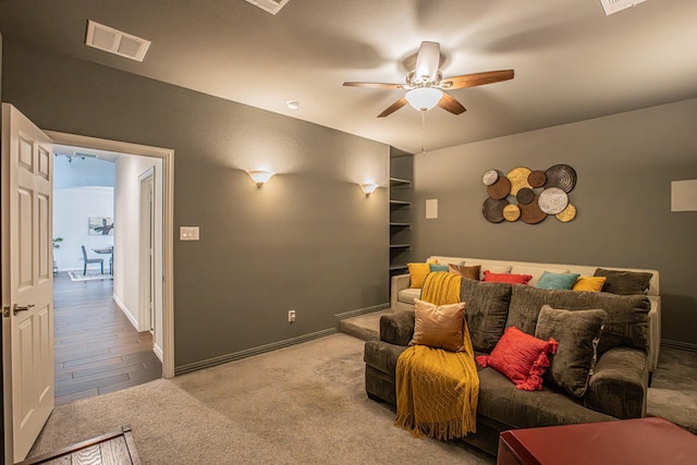 home theater with baseboards, a ceiling fan, visible vents, and light colored carpet