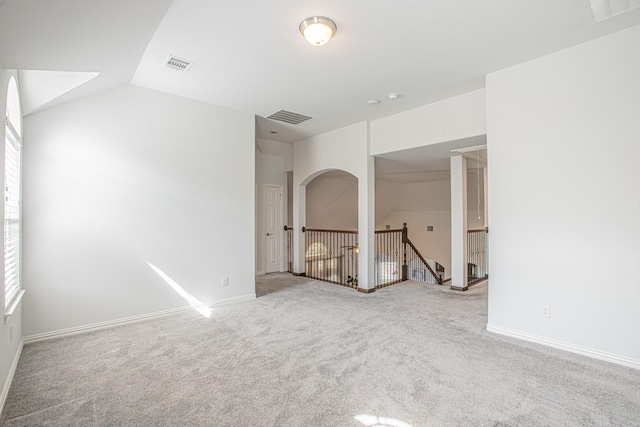 empty room featuring vaulted ceiling, visible vents, and carpet