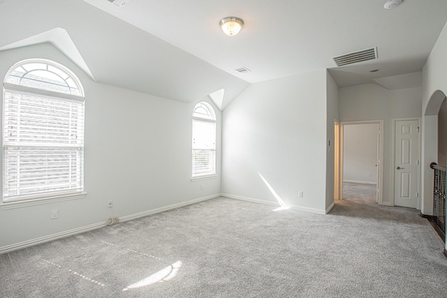 spare room featuring baseboards, vaulted ceiling, visible vents, and carpet