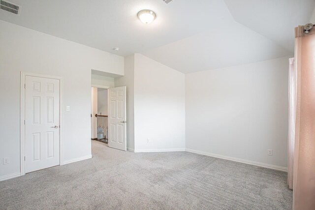 unfurnished bedroom featuring light carpet, lofted ceiling, visible vents, and baseboards