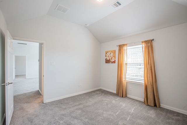 carpeted spare room featuring vaulted ceiling, visible vents, and baseboards