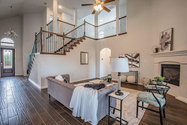 living area featuring wood finish floors, visible vents, high vaulted ceiling, and stairs