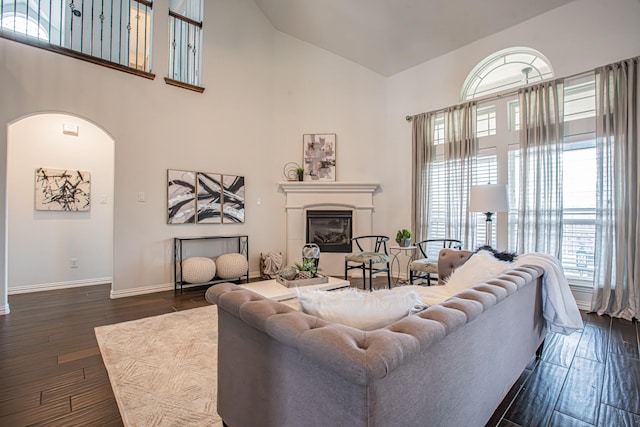 living room with high vaulted ceiling, arched walkways, baseboards, and dark wood-type flooring