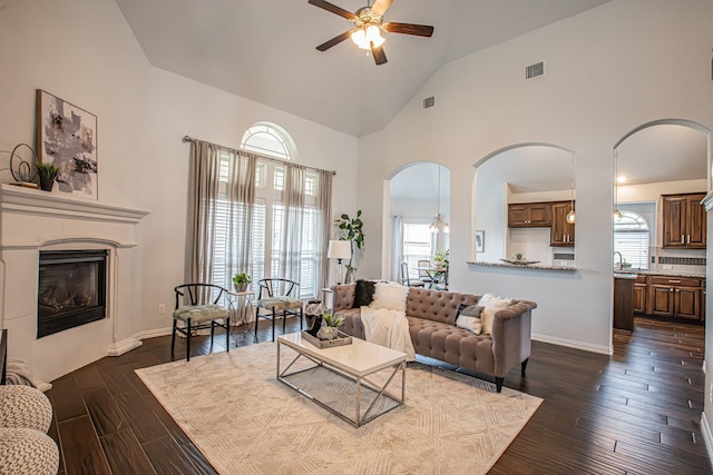 living area featuring visible vents, arched walkways, ceiling fan, and a healthy amount of sunlight
