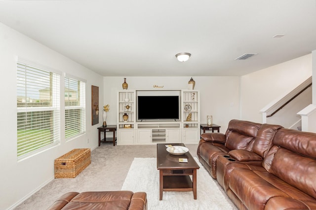 living room featuring light carpet, baseboards, visible vents, and stairs