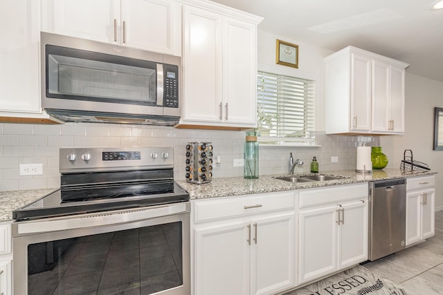 kitchen featuring white cabinets, decorative backsplash, a sink, and appliances with stainless steel finishes