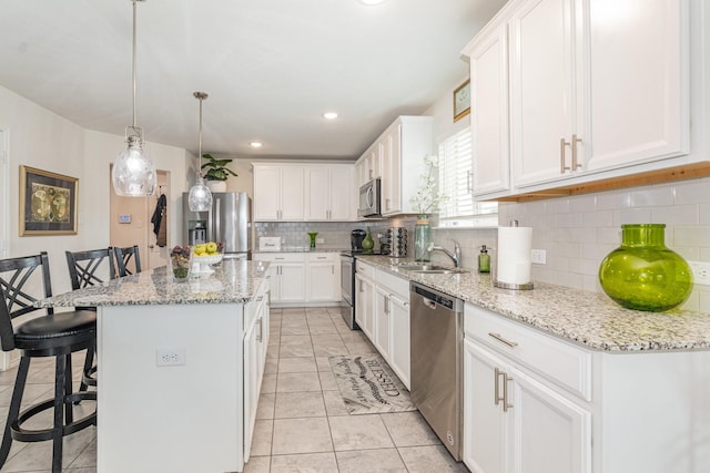 kitchen featuring stainless steel appliances, a center island, a sink, tasteful backsplash, and a breakfast bar
