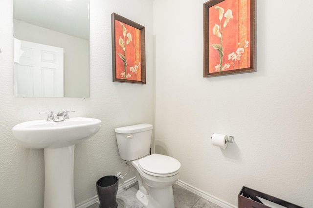 bathroom with tile patterned flooring, toilet, baseboards, and a sink