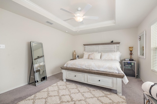 bedroom with a tray ceiling, visible vents, light carpet, crown molding, and baseboards