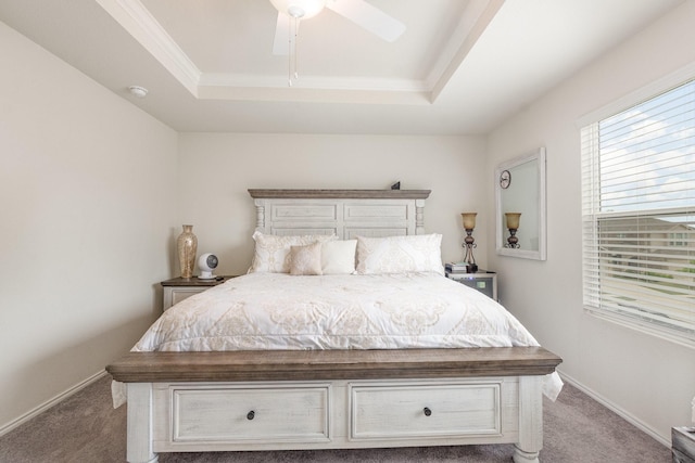 carpeted bedroom with a tray ceiling, ornamental molding, baseboards, and ceiling fan