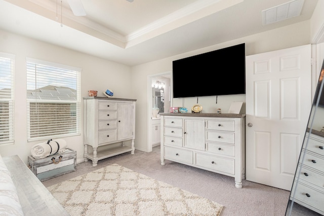 bedroom featuring a raised ceiling, visible vents, light colored carpet, connected bathroom, and ornamental molding