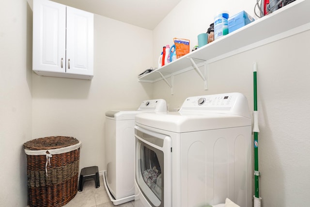washroom with washer and clothes dryer, light tile patterned floors, and cabinet space