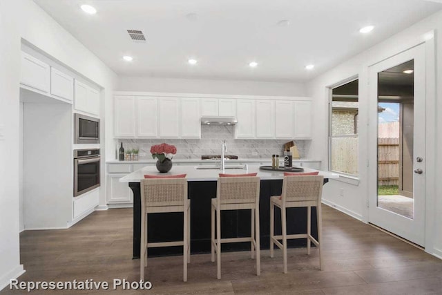 3705 Hickory St, Sherman, TX 75092 - kitchen featuring white cabinets, under cabinet range hood, light countertops, visible vents, and appliances with stainless steel finishes