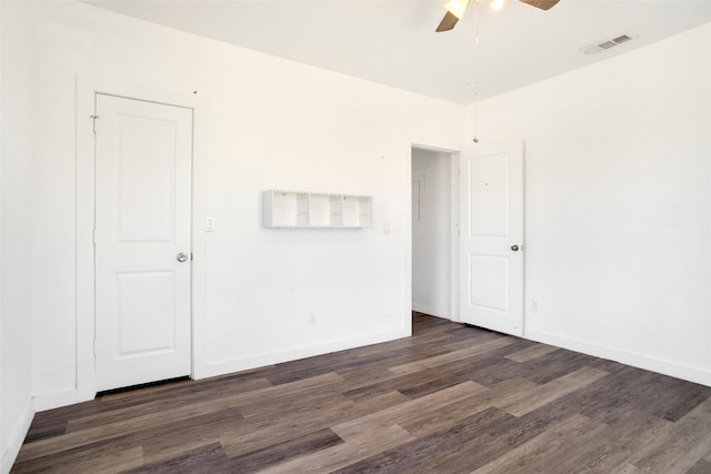 empty room with baseboards, a ceiling fan, wood finished floors, and visible vents