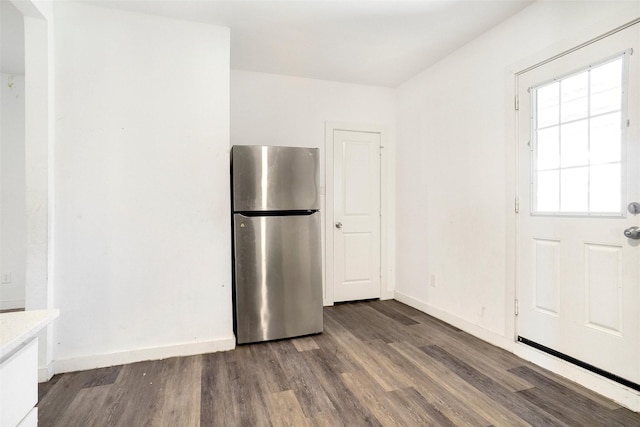 kitchen featuring dark wood-type flooring, freestanding refrigerator, light countertops, and baseboards