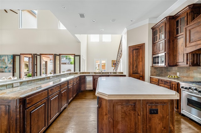 6511 Mimosa Ln, Dallas, TX 75230 - kitchen featuring appliances with stainless steel finishes, a large island, light countertops, backsplash, and glass insert cabinets
