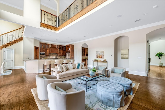6511 Mimosa Ln, Dallas, TX 75230 - living room with a high ceiling, ornamental molding, arched walkways, wood finished floors, and baseboards
